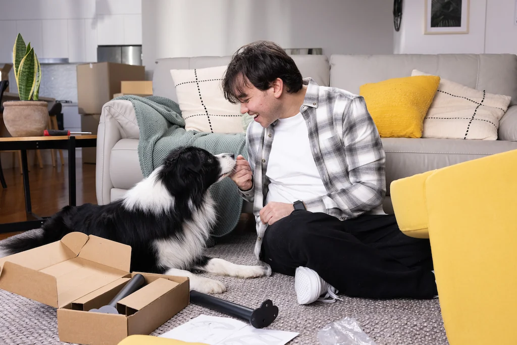 Man sitting with dog putting furniture together