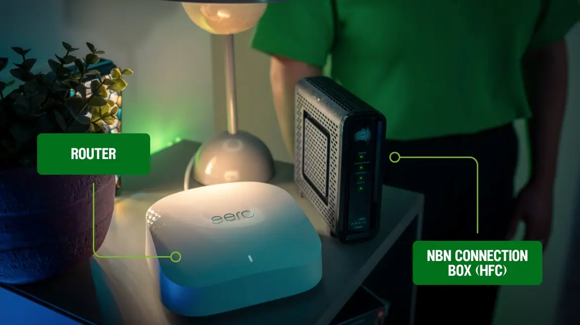 Image a person standing next to a eero router and nbn modem.